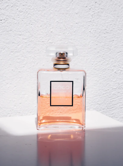 Minimalist serum bottle on a soft peach background with natural light highlighting its texture.