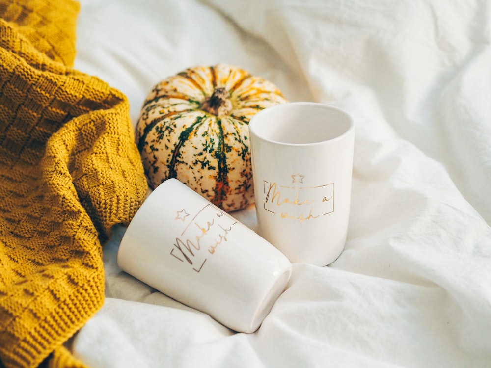 white ceramic mug beside yellow and white textile