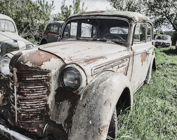 an old rusty car is sitting in the grass