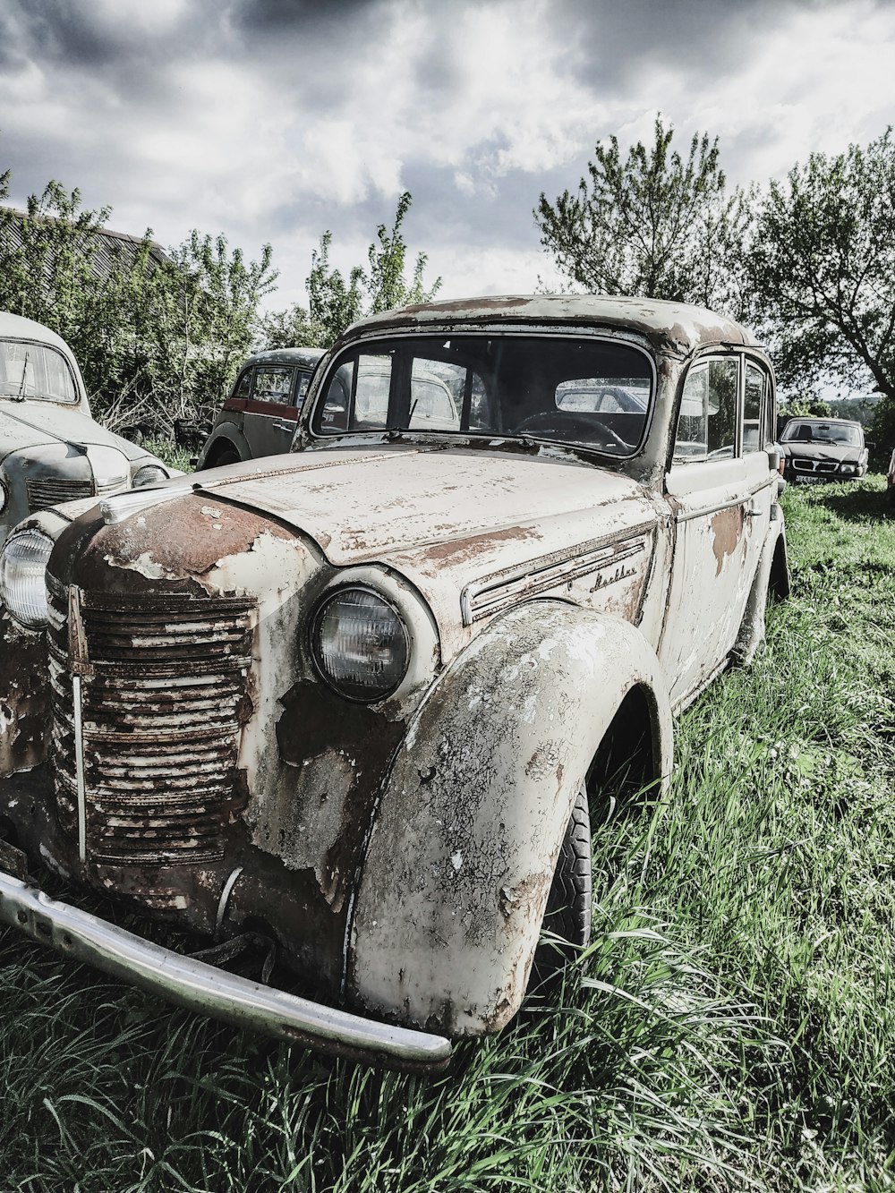 an old rusty car is sitting in the grass