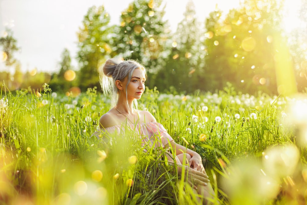 woman in white floral dress sitting on green grass field during daytime