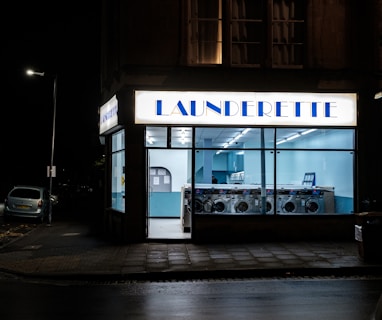 a store front at night with a car parked in front of it