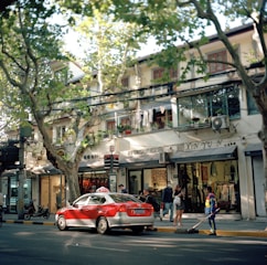 A taxi driving through a charming Folkestone street lined with shops.