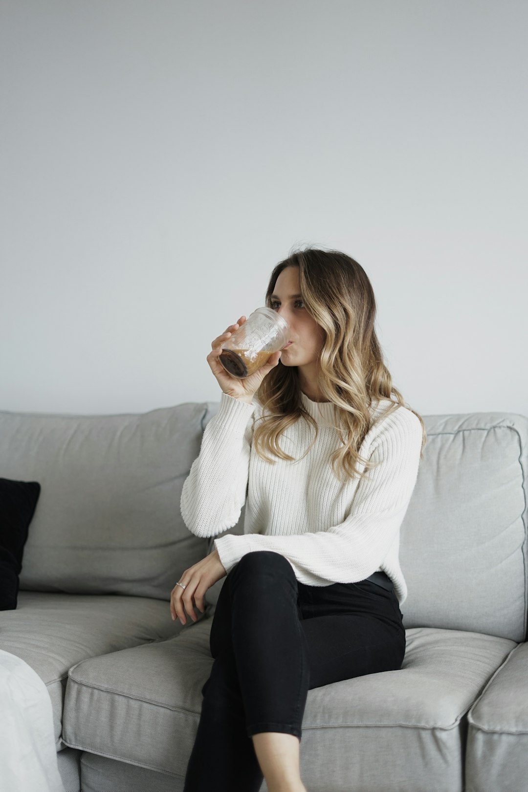 woman in white sweater and black pants sitting on couch