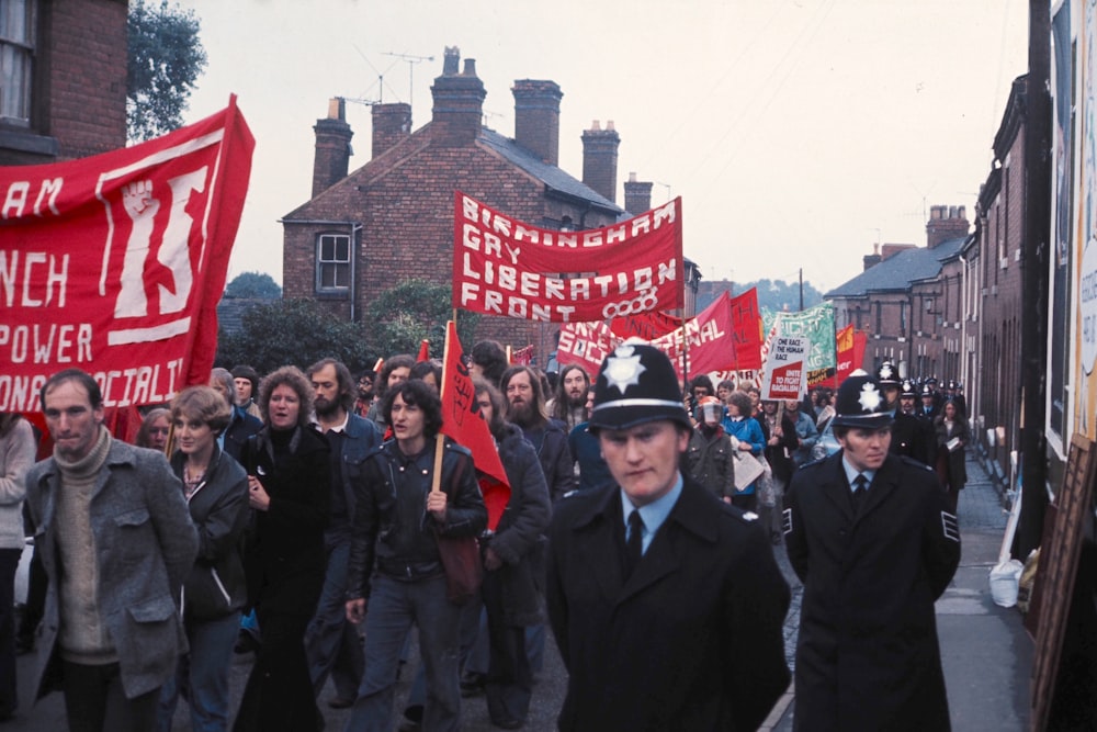 Menschen in schwarzem Anzug, die tagsüber in der Nähe der rot-weißen Flagge stehen