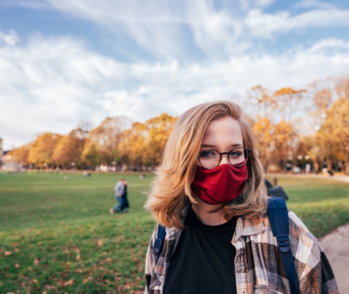 woman in black leather jacket wearing black sunglasses standing on green grass field during daytime