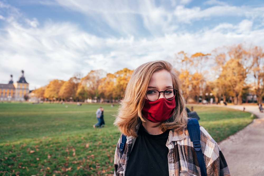 Frau in schwarzer Lederjacke mit schwarzer Sonnenbrille tagsüber auf grünem Rasen