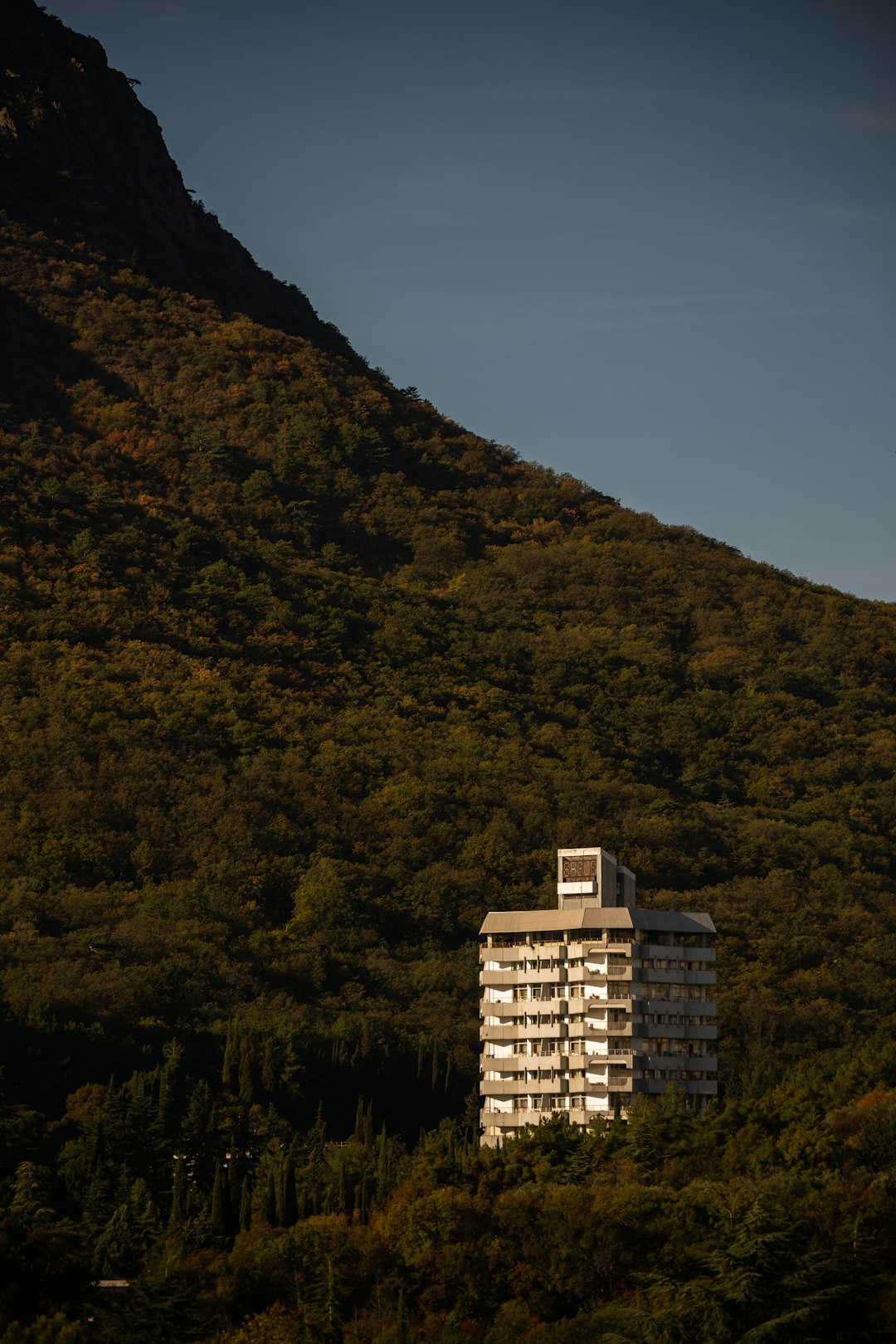 white concrete building near green mountain during daytime