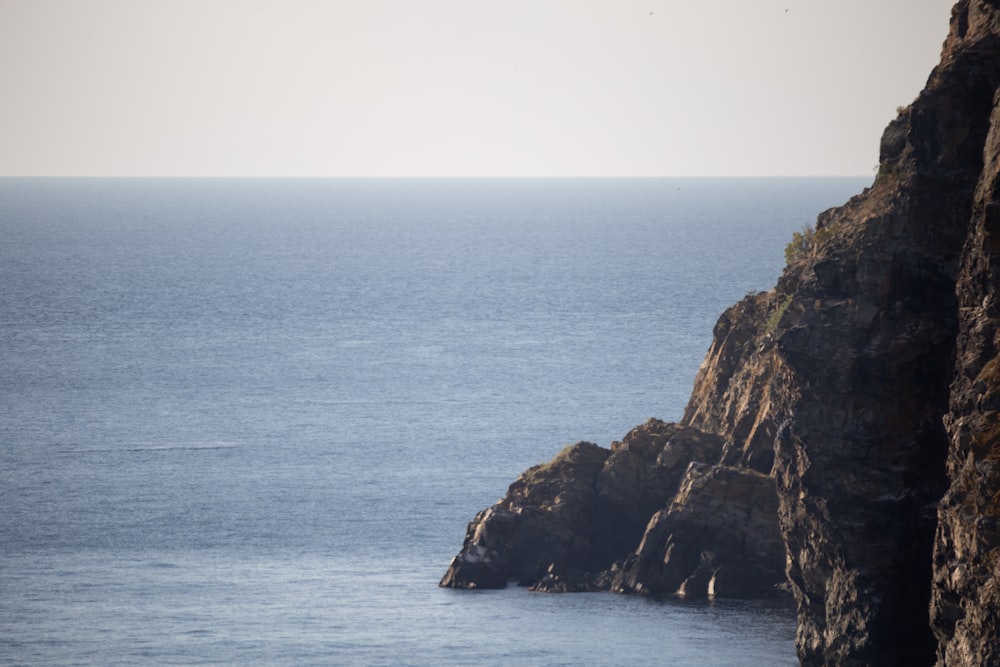 brown rock formation beside body of water during daytime