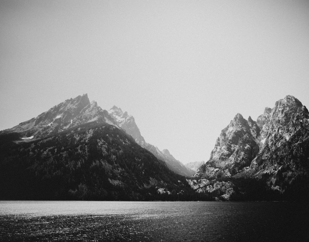 grayscale photo of mountains near body of water