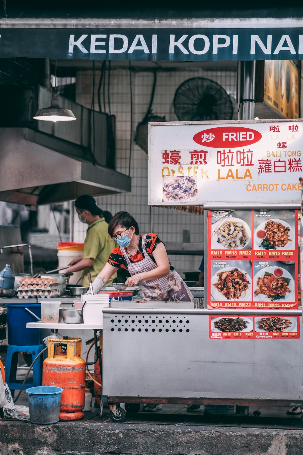 woman in black and white stripe shirt standing in front of food stall