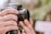 A close-up of a photographer adjusting a DSLR camera lens in natural light.