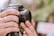 A close-up of a photographer adjusting their camera, surrounded by natural scenery.