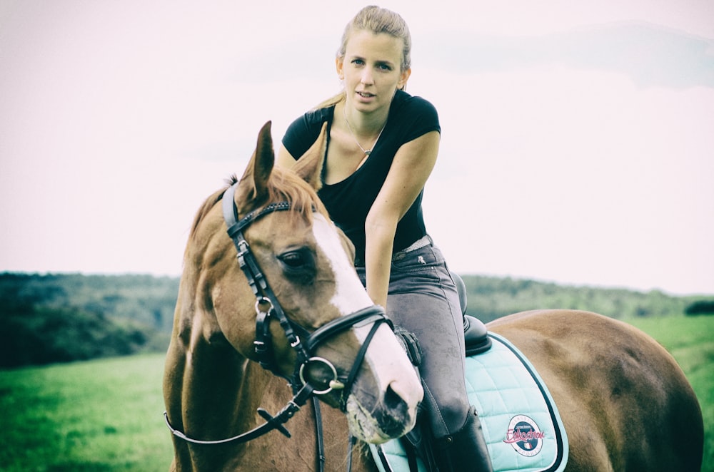 Junge im schwarz-weiß gestreiften Poloshirt reitet tagsüber auf weißem Pferd