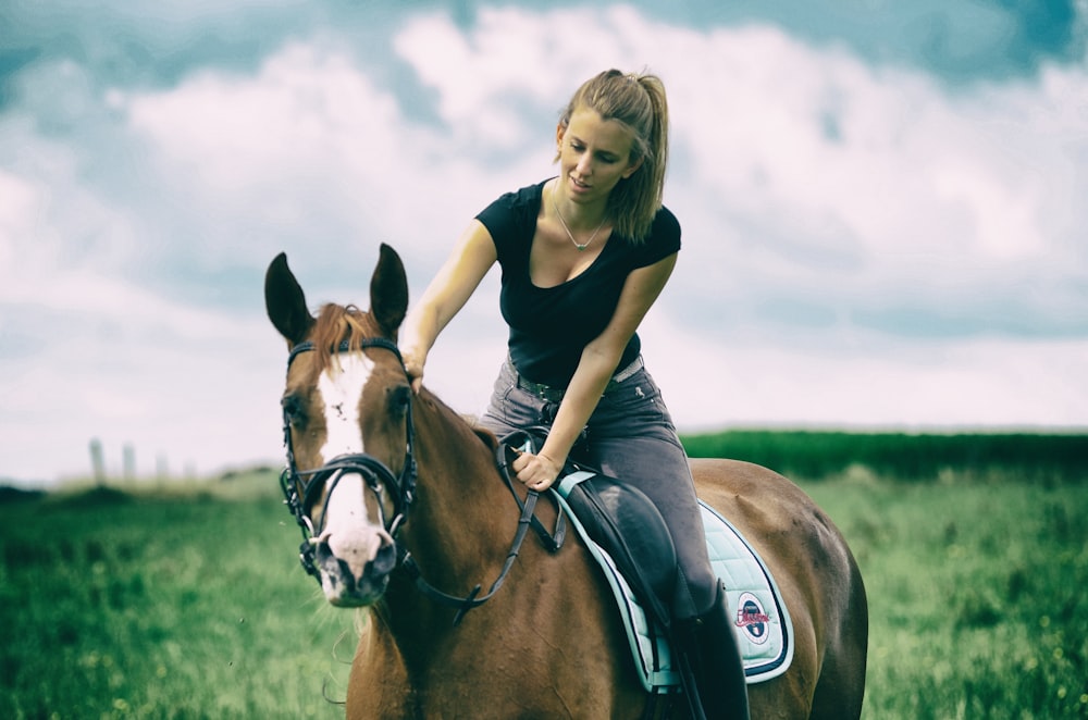 girl in black shirt riding brown horse during daytime