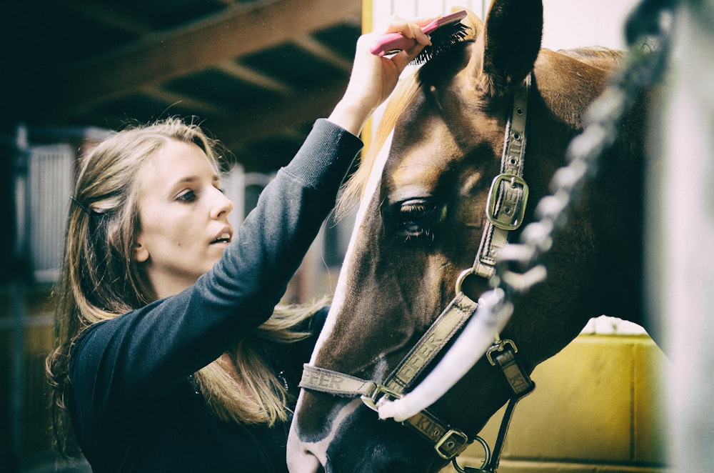 woman in black leather jacket holding horse head