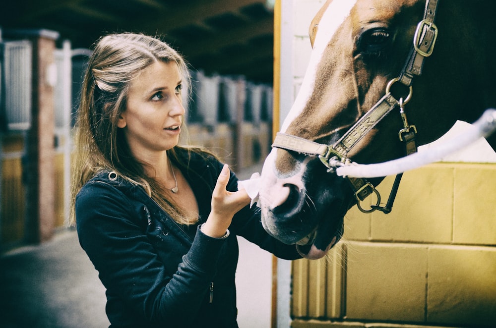 woman in black long sleeve shirt holding white horse head during daytime