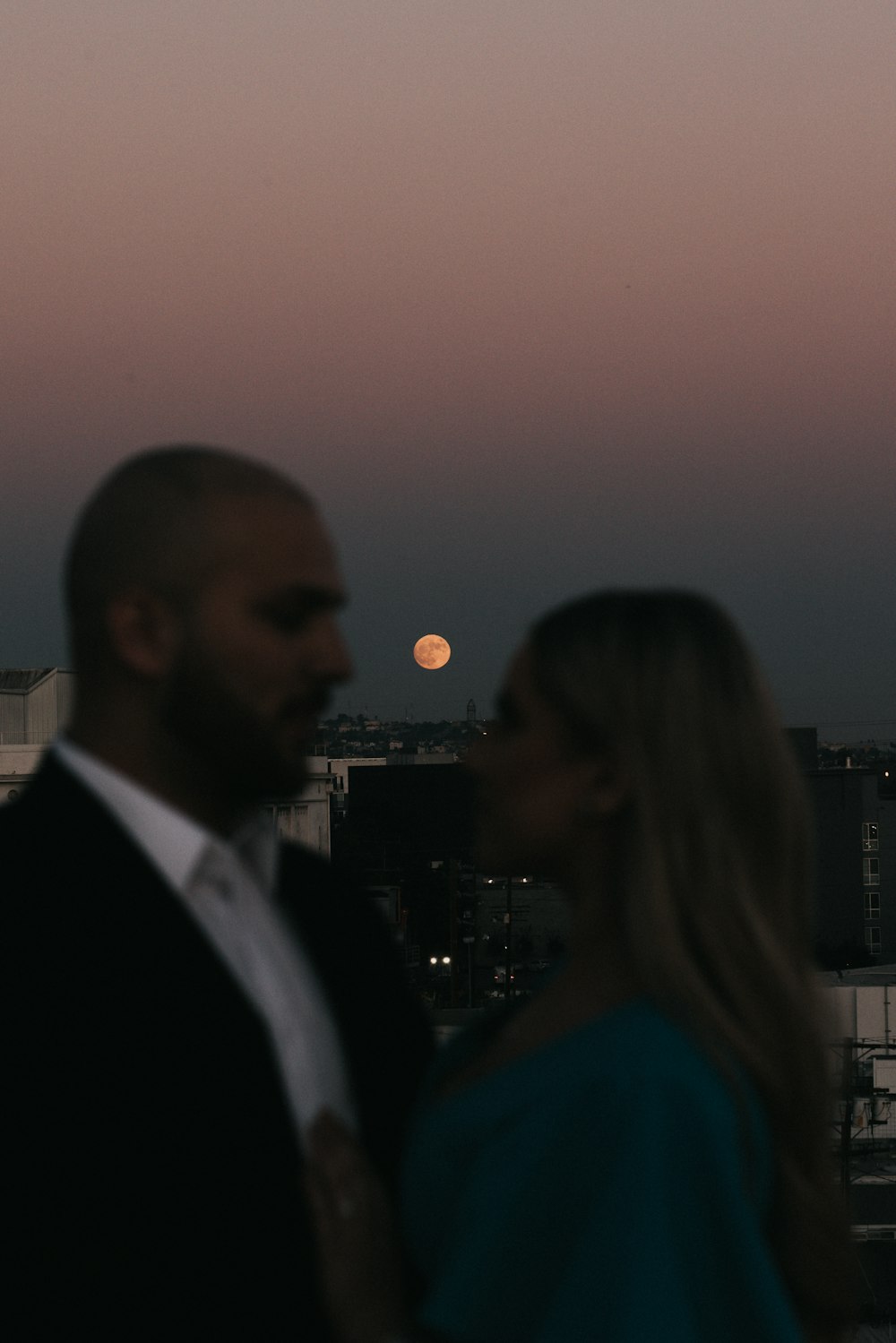 man in black suit jacket standing beside woman in blue shirt