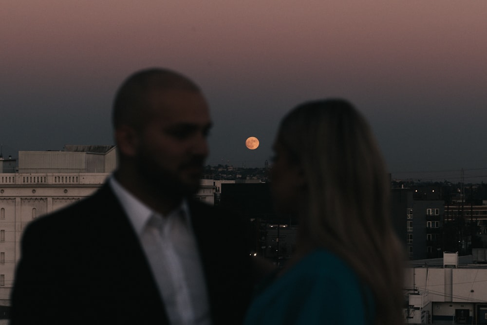 man in black suit jacket beside woman in blue shirt