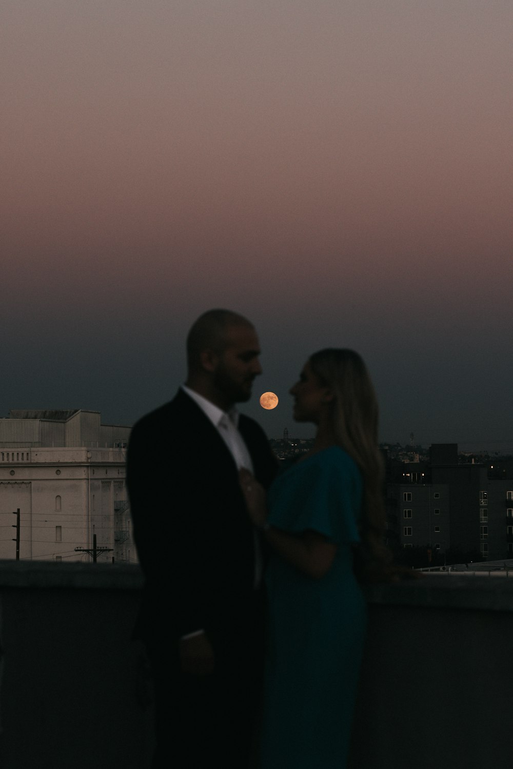 man in black suit jacket standing beside woman in blue dress during daytime