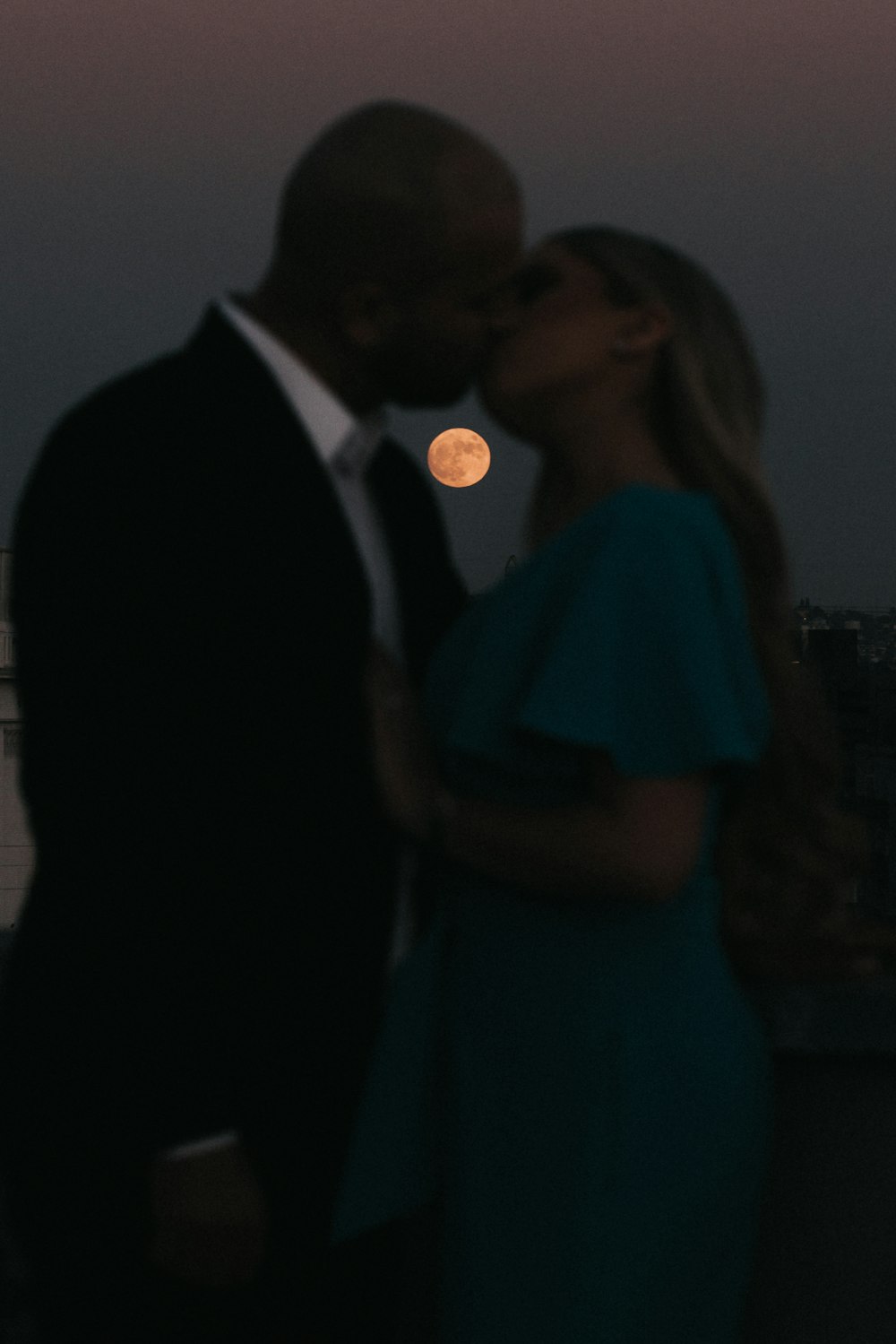 man in black suit standing beside woman in teal dress