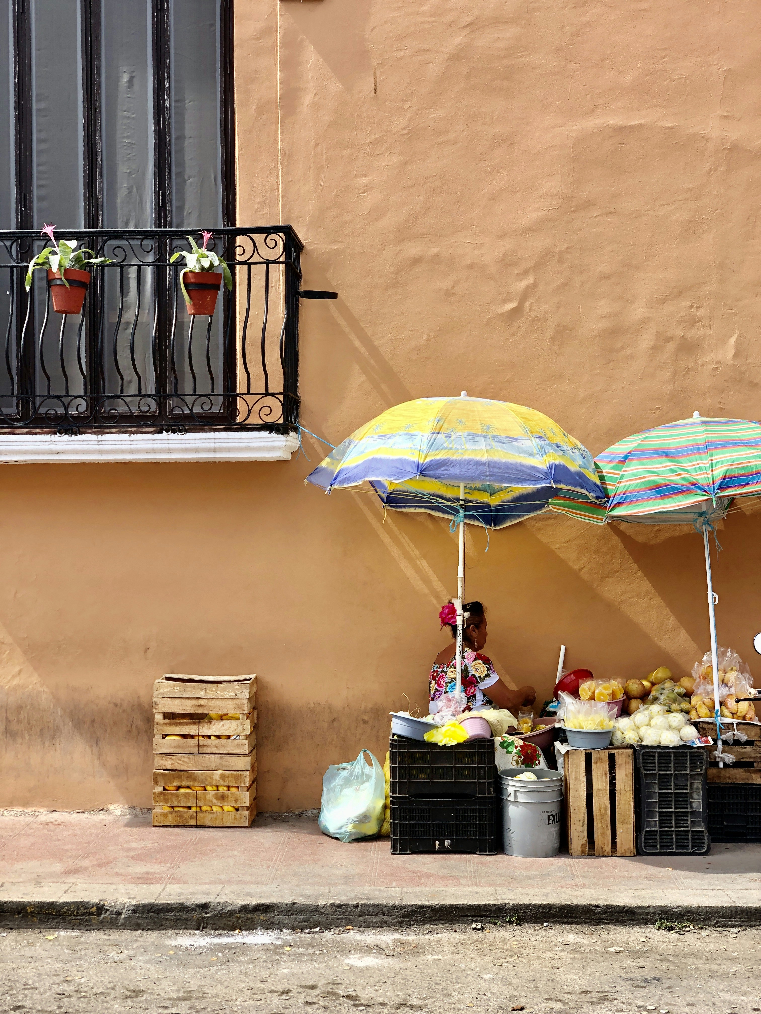 a woman sitting under an umbrella on the side of a building