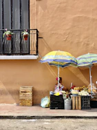 a woman sitting under an umbrella on the side of a building