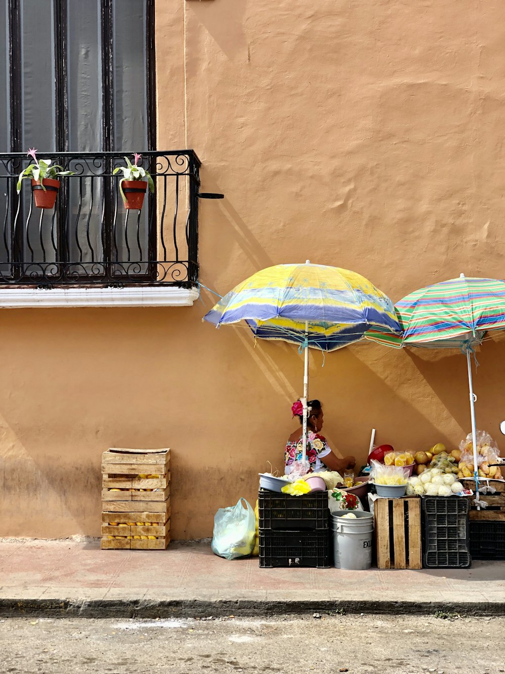 a woman sitting under an umbrella on the side of a building