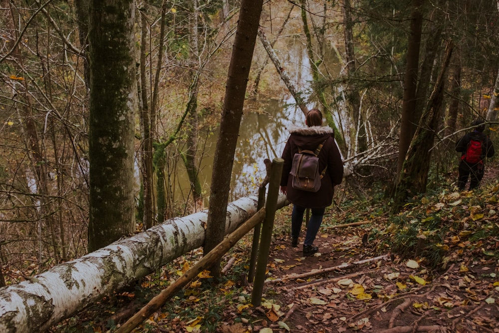 Frau in schwarzer Jacke und schwarzer Hose geht tagsüber im Wald spazieren