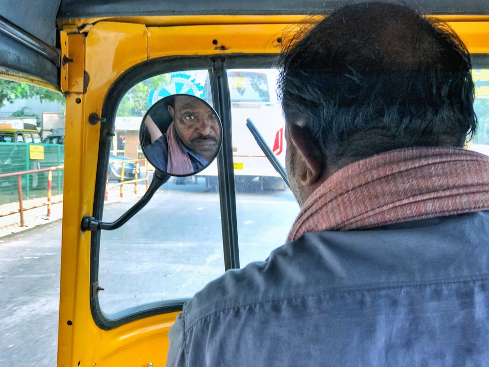 a man looking at himself in the mirror of a bus