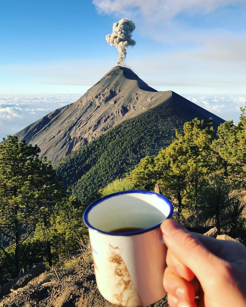 a cup of coffee with a volcano in the background