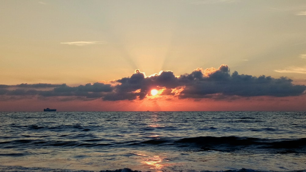 ocean waves under cloudy sky during sunset