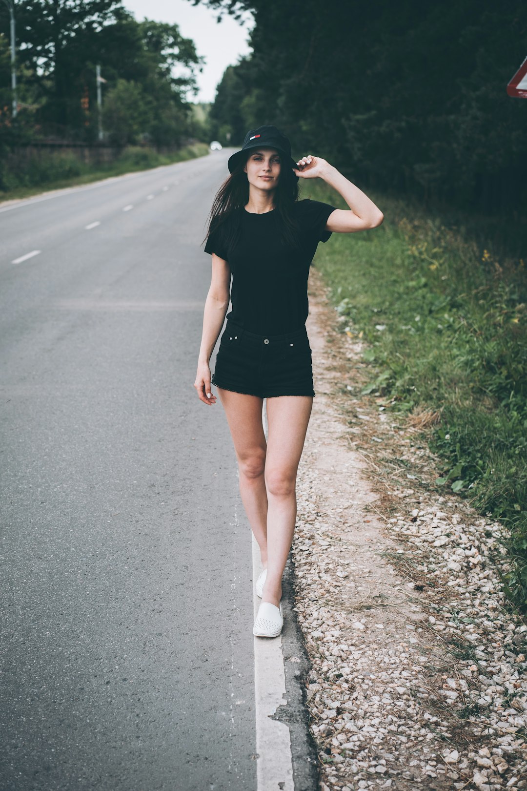 woman in black crew neck t-shirt and black shorts walking on gray asphalt road during
