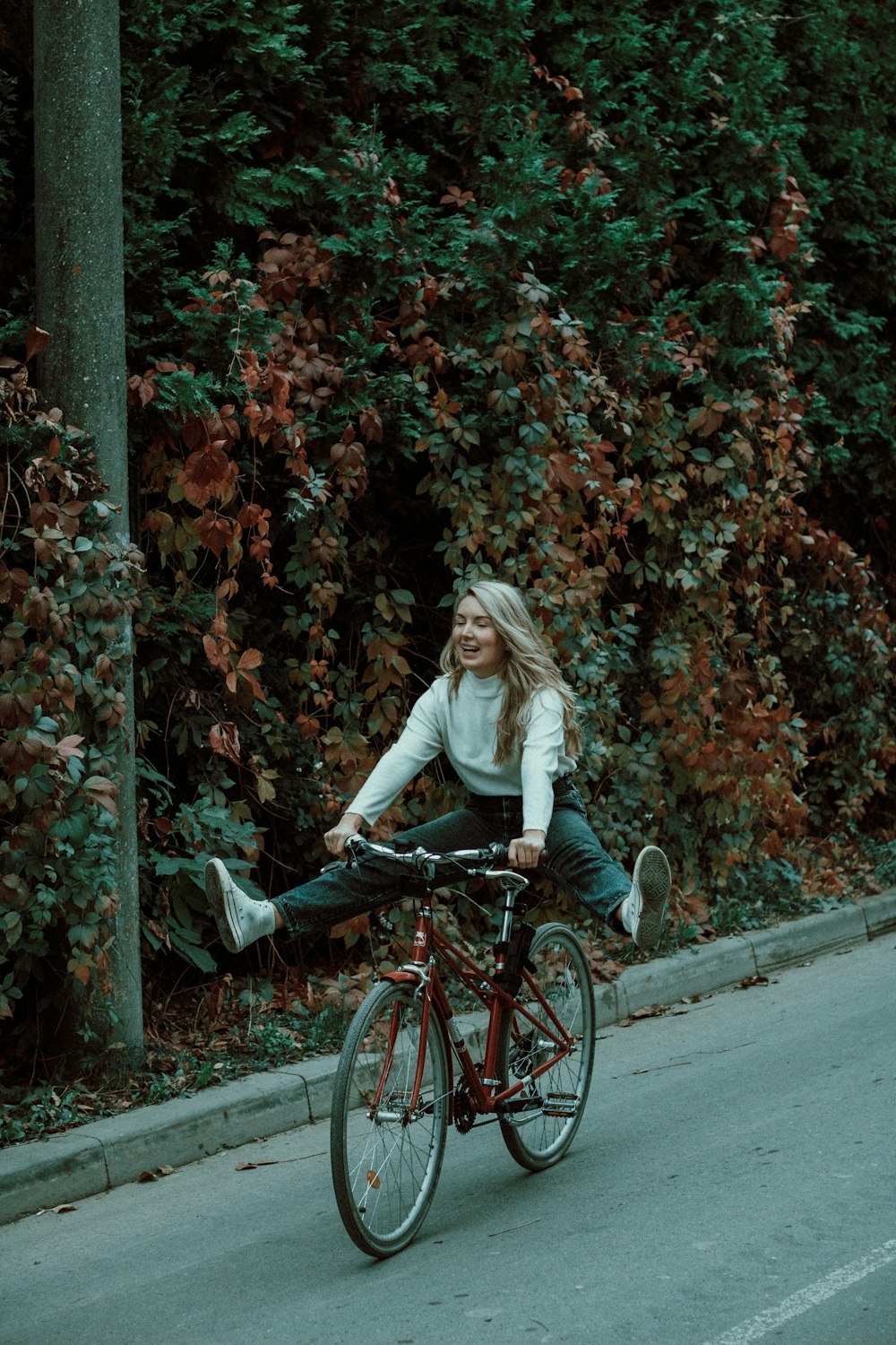 woman in white long sleeve shirt riding on black bicycle on road during daytime