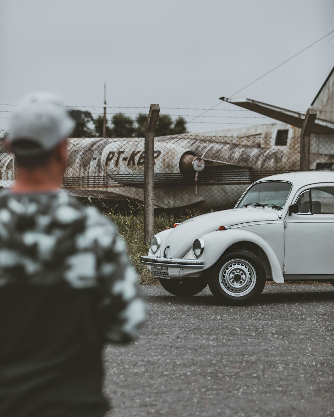 man in black and white camouflage jacket standing beside white car during daytime