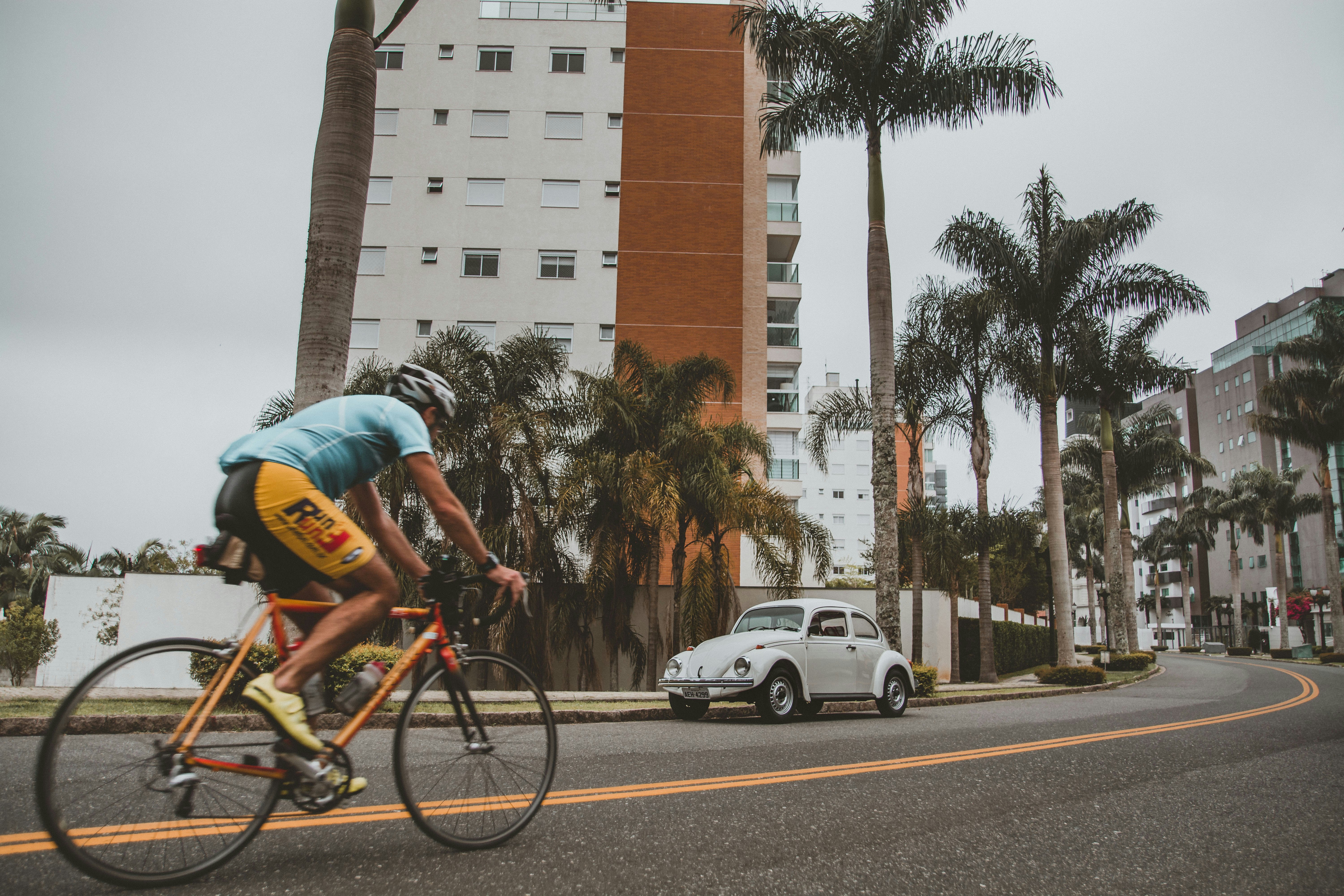 man in blue shirt riding on bicycle on road during daytime