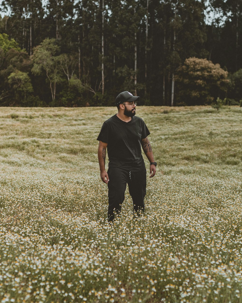 man in black crew neck t-shirt and black pants standing on green grass field during