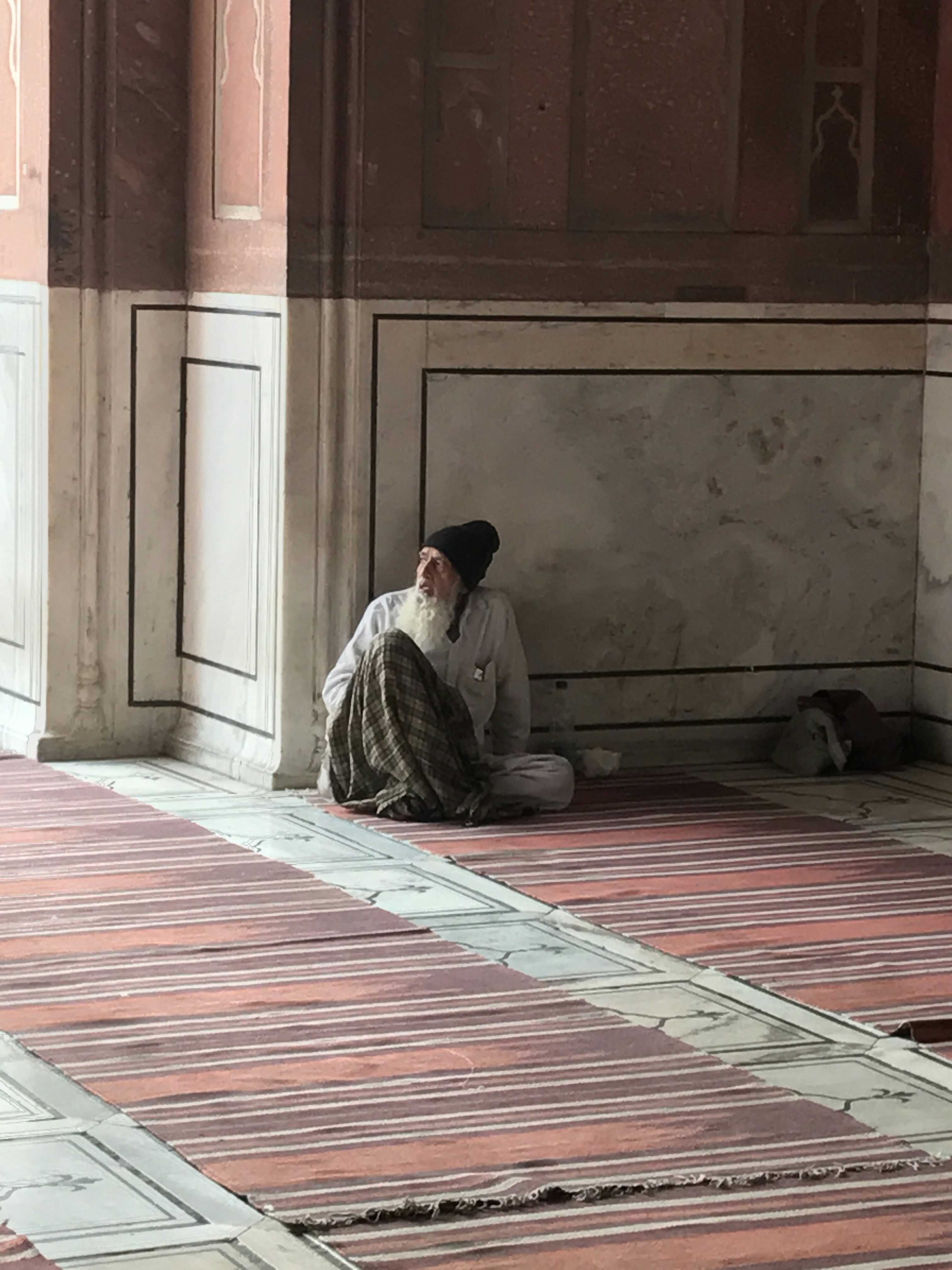 man in white thobe sitting on red and white floor