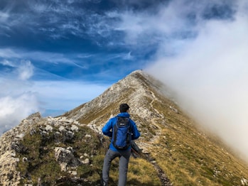 man in blue jacket and gray pants standing on green grass field during daytime