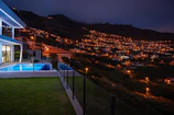 A nighttime 3D visualization of a contemporary villa with illuminated pathways and a reflective pool.