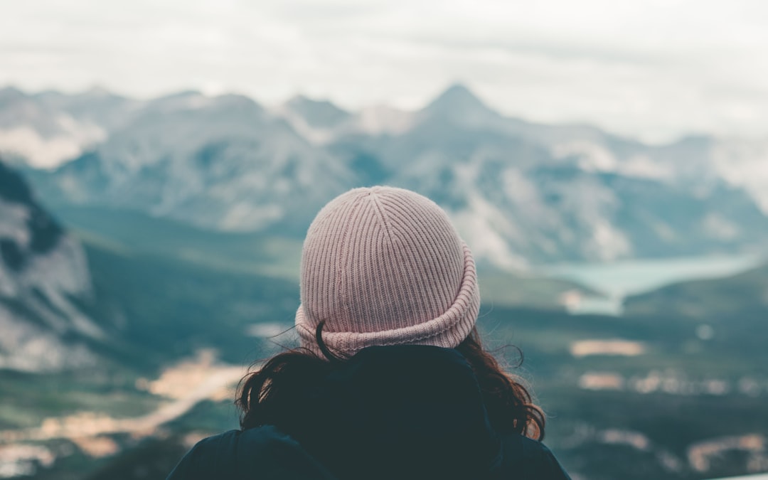 woman in white knit cap looking at mountains during daytime