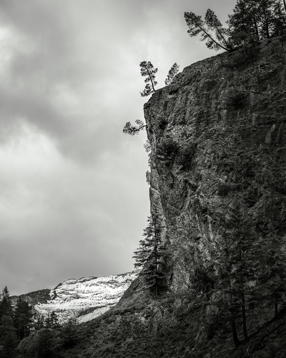 Photo en niveaux de gris d’une personne grimpant sur une montagne