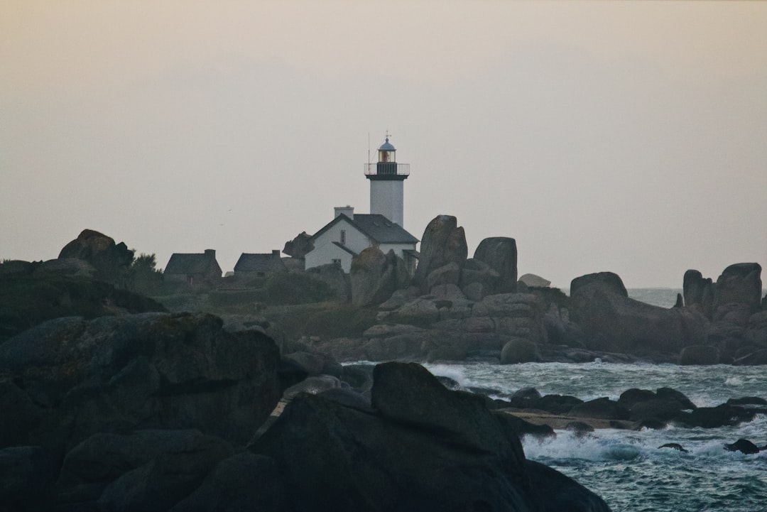 white and black lighthouse on rocky shore during daytime