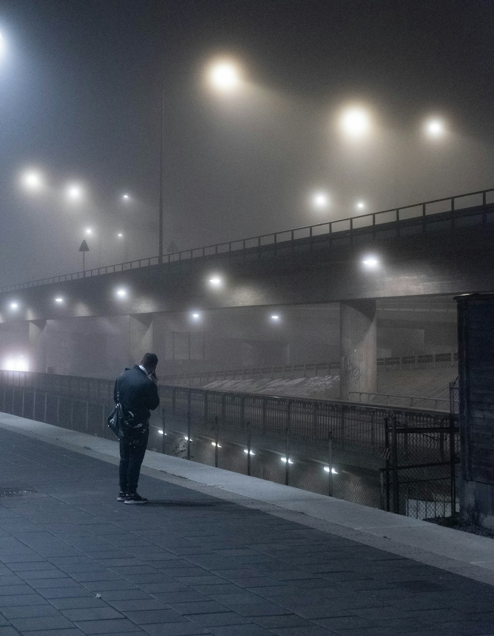 uomo in giacca nera che cammina sul marciapiede durante la notte