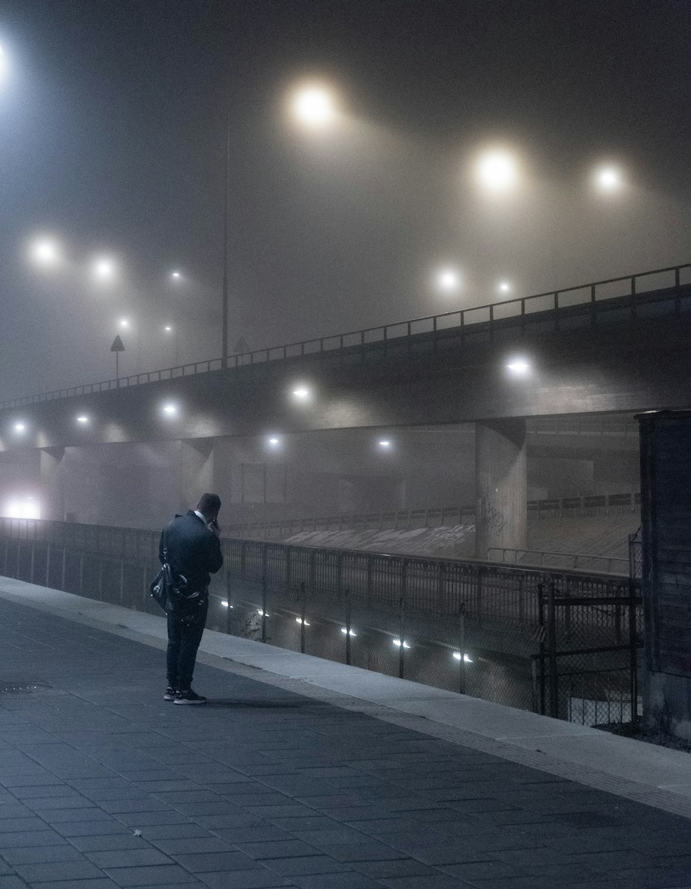 homem em jaqueta preta andando na calçada durante a noite