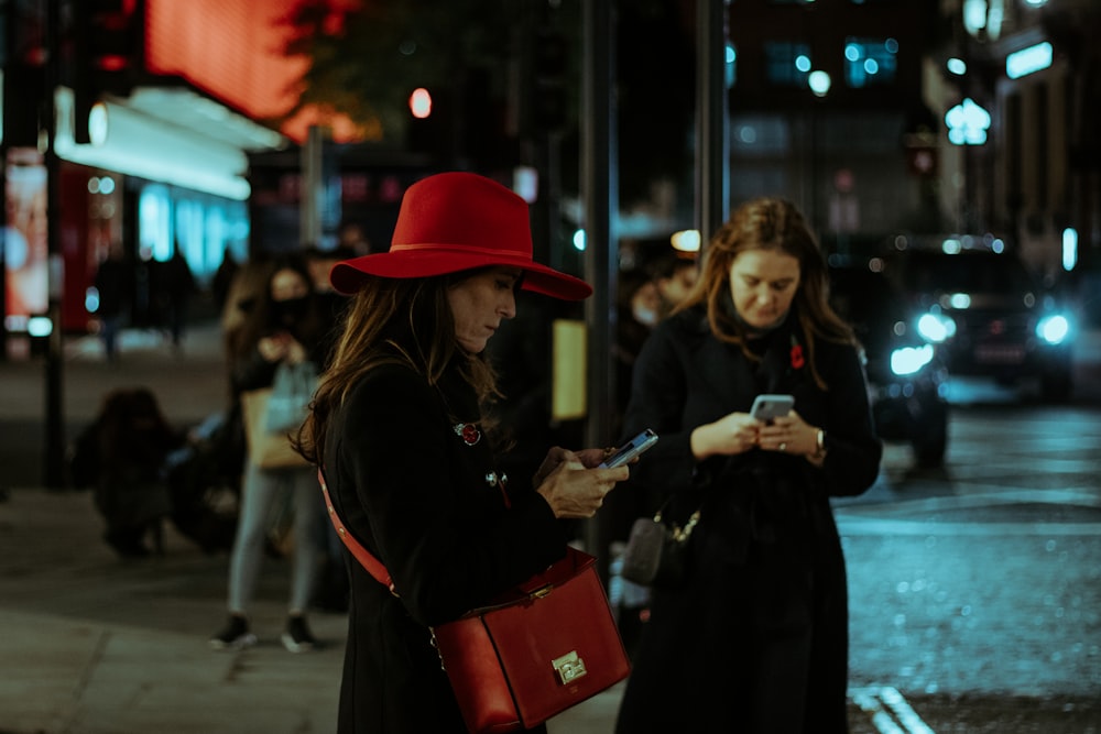 woman in black coat and red hat holding red plastic container