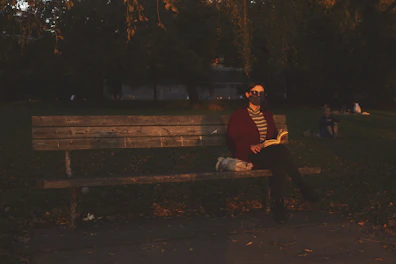 A person reading an ebook on a park bench at sunset.