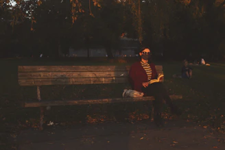 A person reading an ebook on a park bench at sunset.