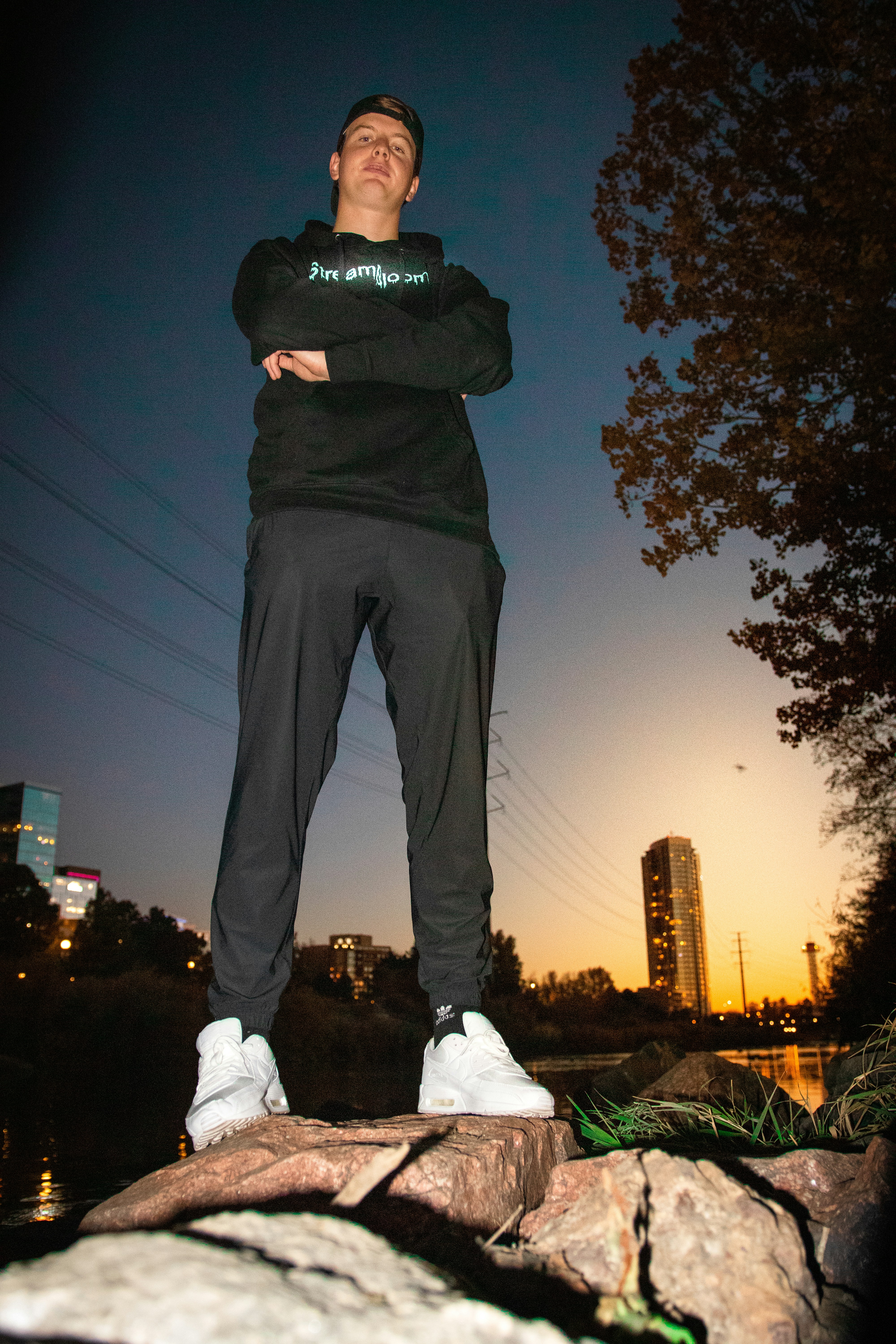 man in black jacket and gray pants standing on brown wooden seat during night time