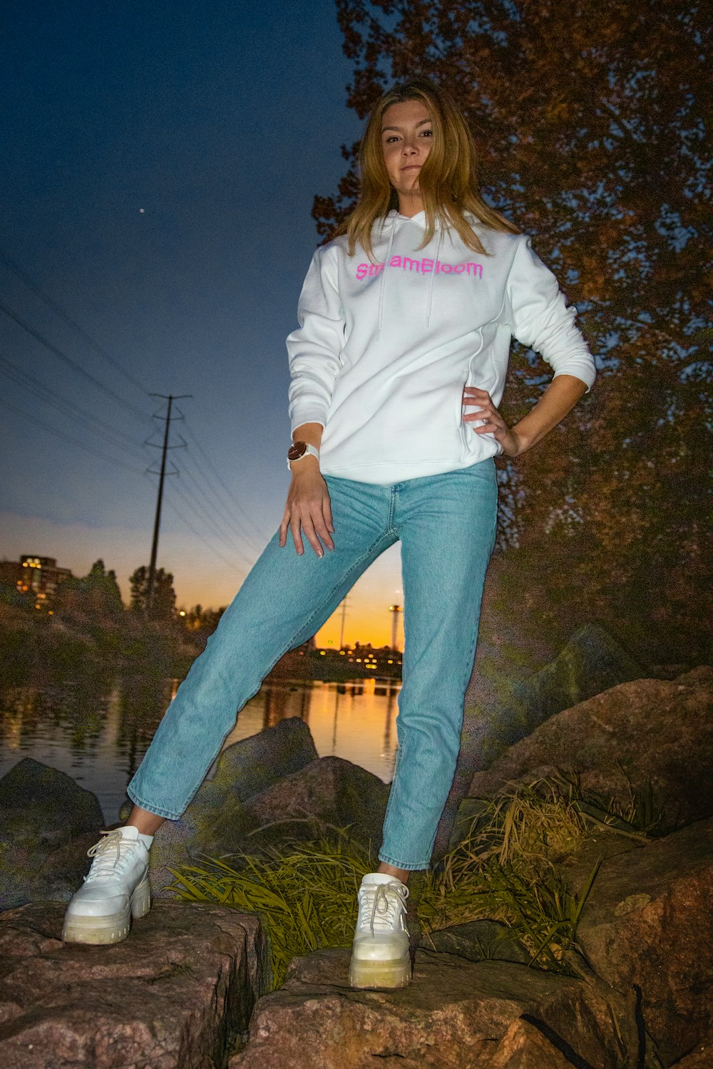 woman in white long sleeve shirt and blue denim jeans standing on brown rock near body